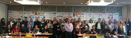 Photo des participants à la convention annuelle sur fond des dessins issus du concours « Carnaval : déguise ta mascotte »